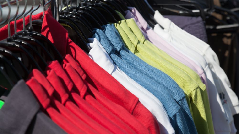A row of clothing hangers displays polo shirts in various colors, including red, blue, green, white, and purple—perfect for showcasing your franchise's success.
