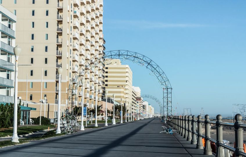A beachfront promenade lined with tall buildings and metal archways on a clear day.